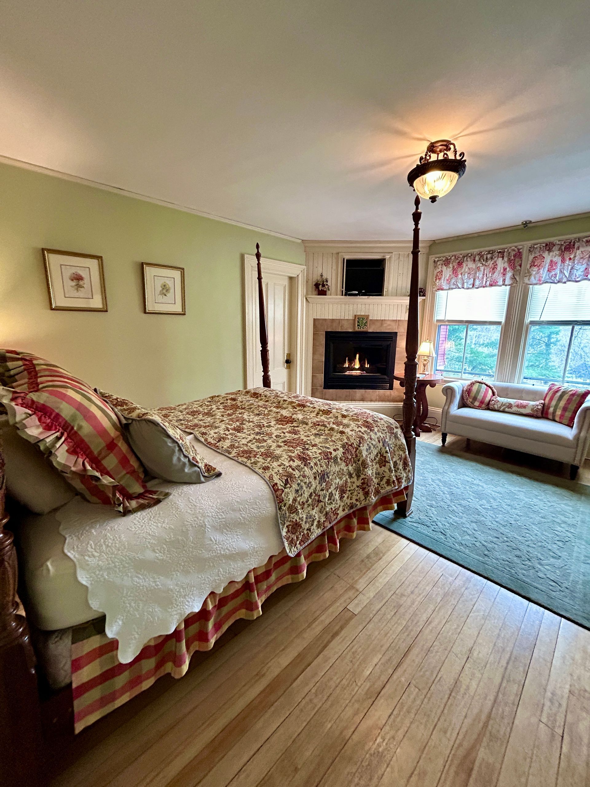A bedroom with a four poster bed and a fireplace.