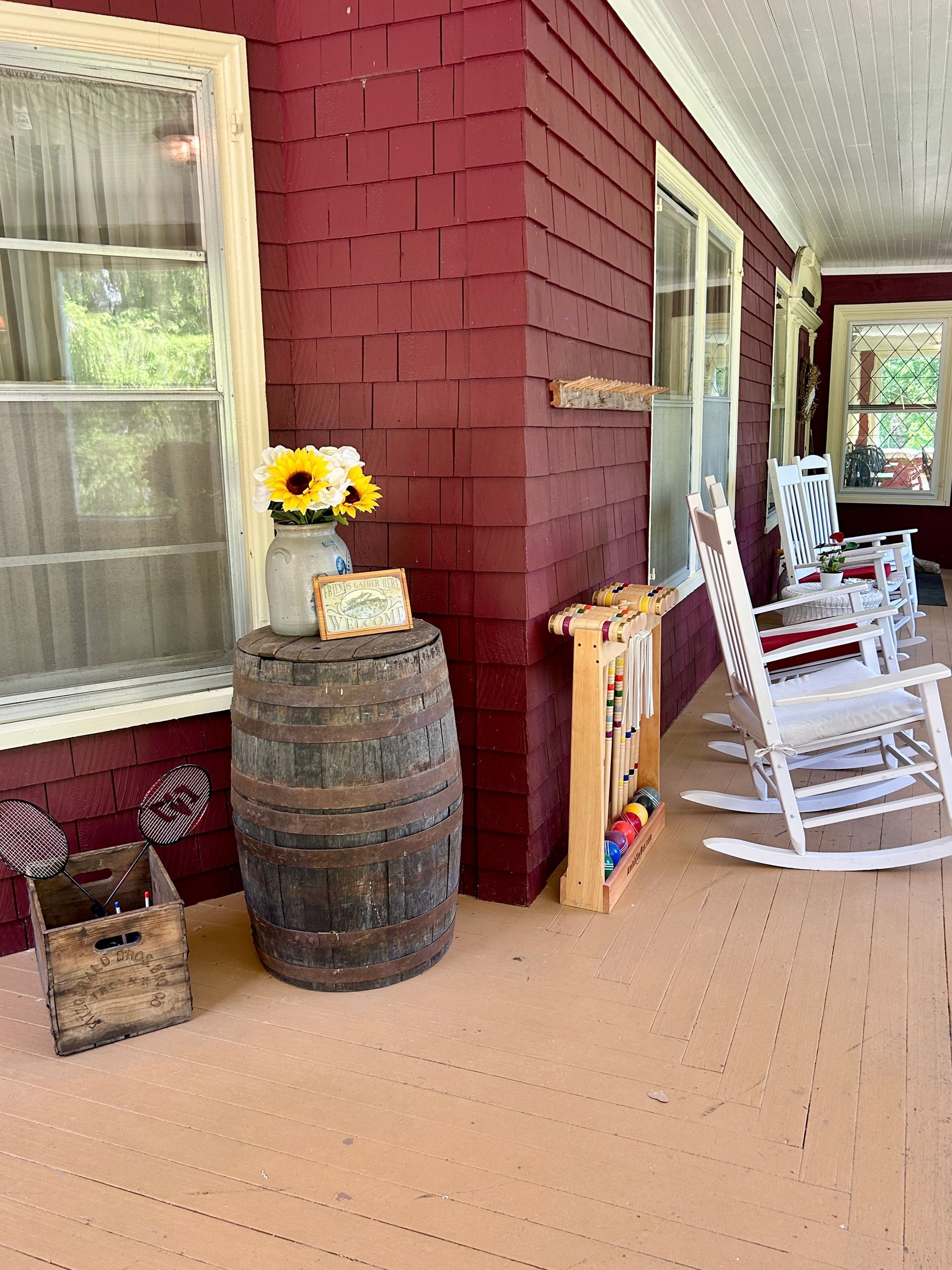 A porch with rocking chairs and a barrel on it.