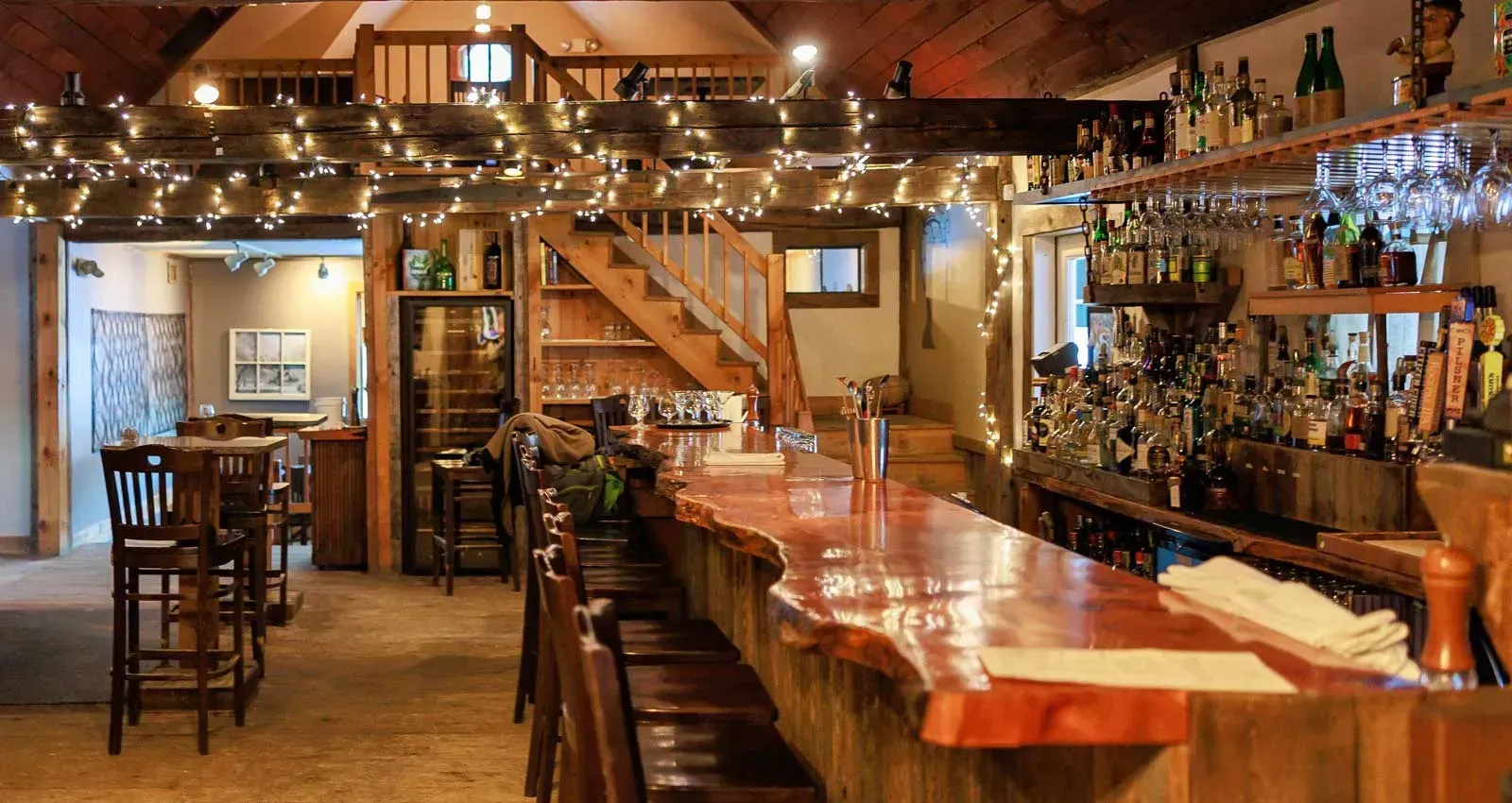 A restaurant with a long wooden bar and stools