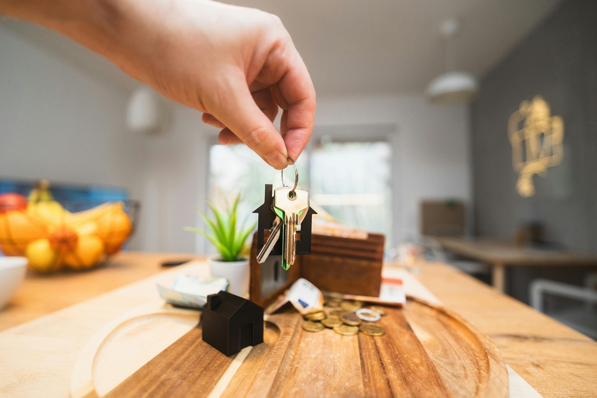 A person is putting a key into a house keychain on a wooden table.