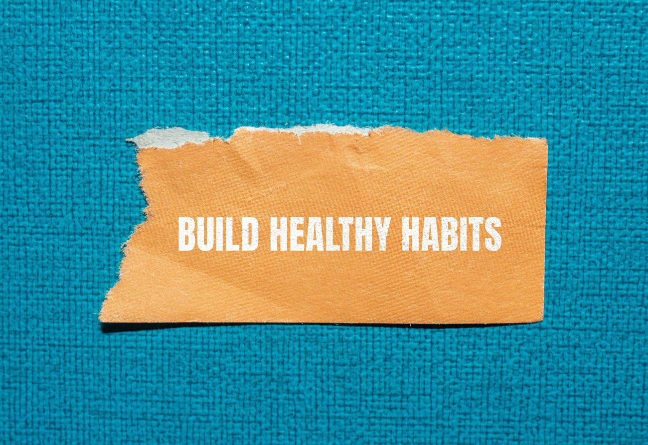 Orange torn paper with “BUILD HEALTHY HABITS” on a blue textured background