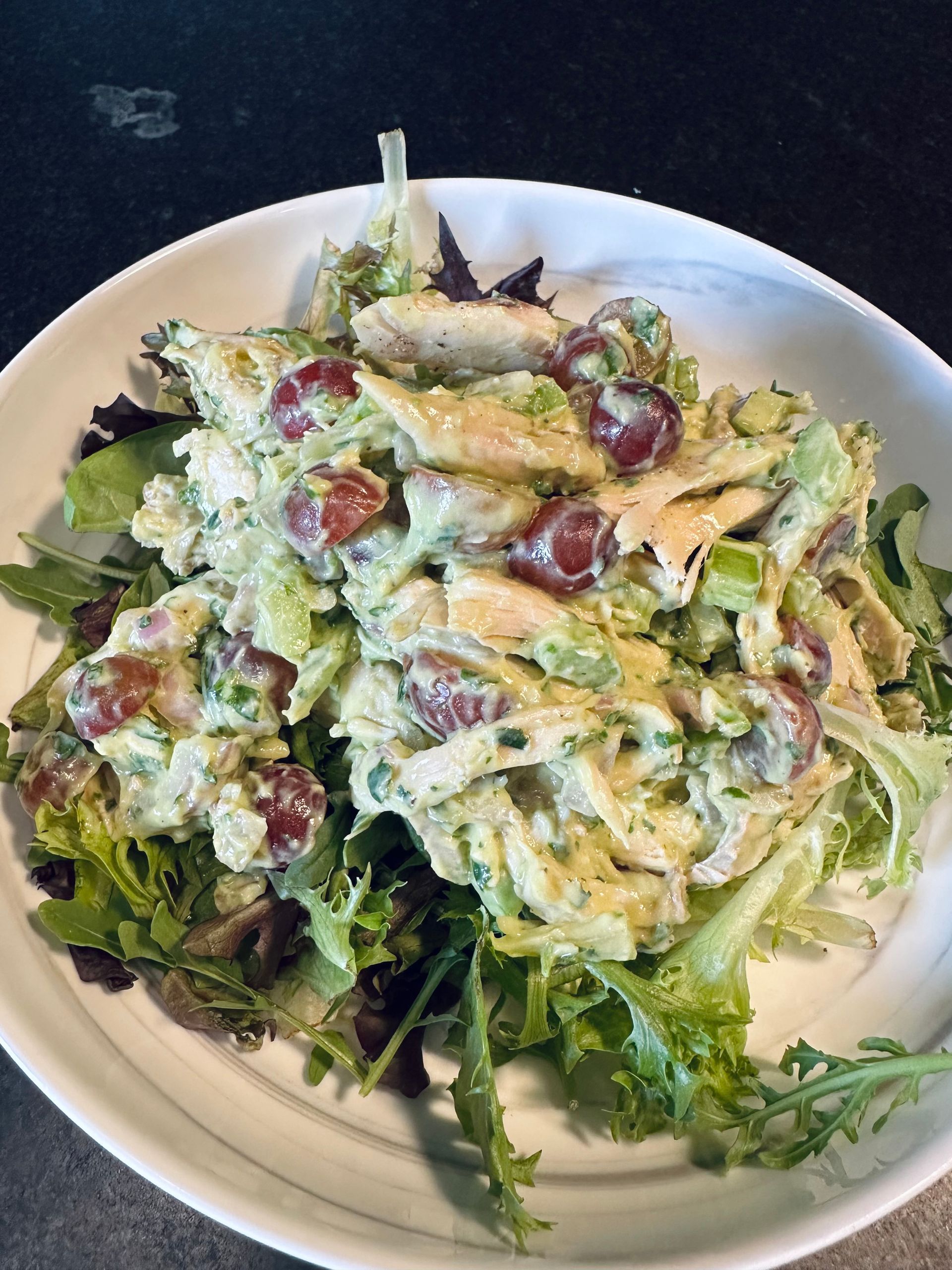 Plate of green salad with grapes and creamy dressing on a white dish