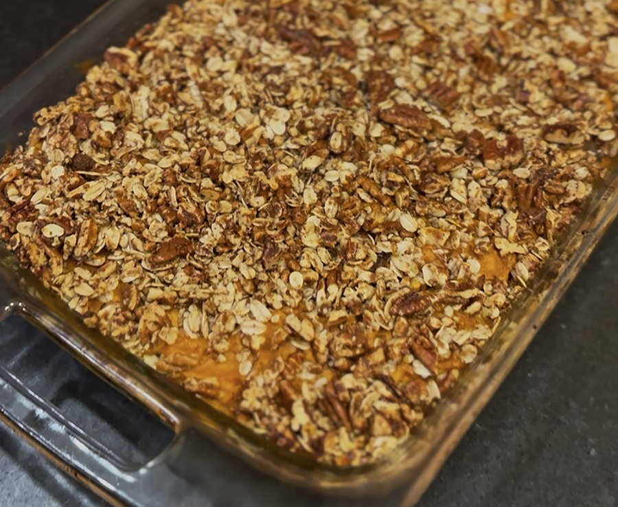 Baked oat and nut topping in a glass baking dish on a dark countertop