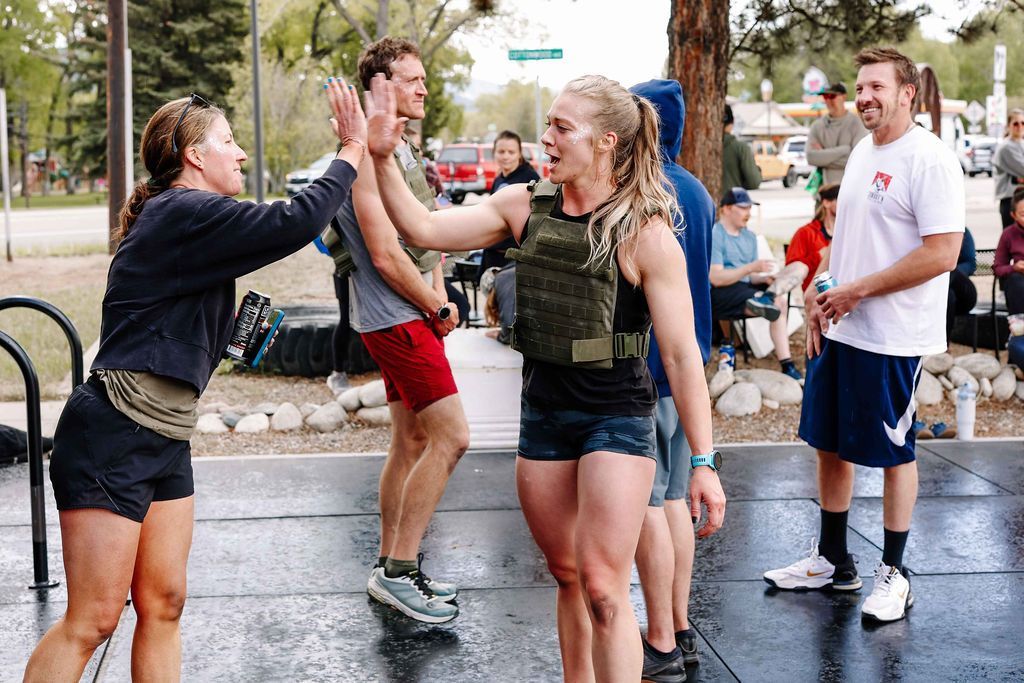 People cheering and high-fiving outdoors on a wet street during a lively event at Fortitude Fitness in Buena Vista, CO