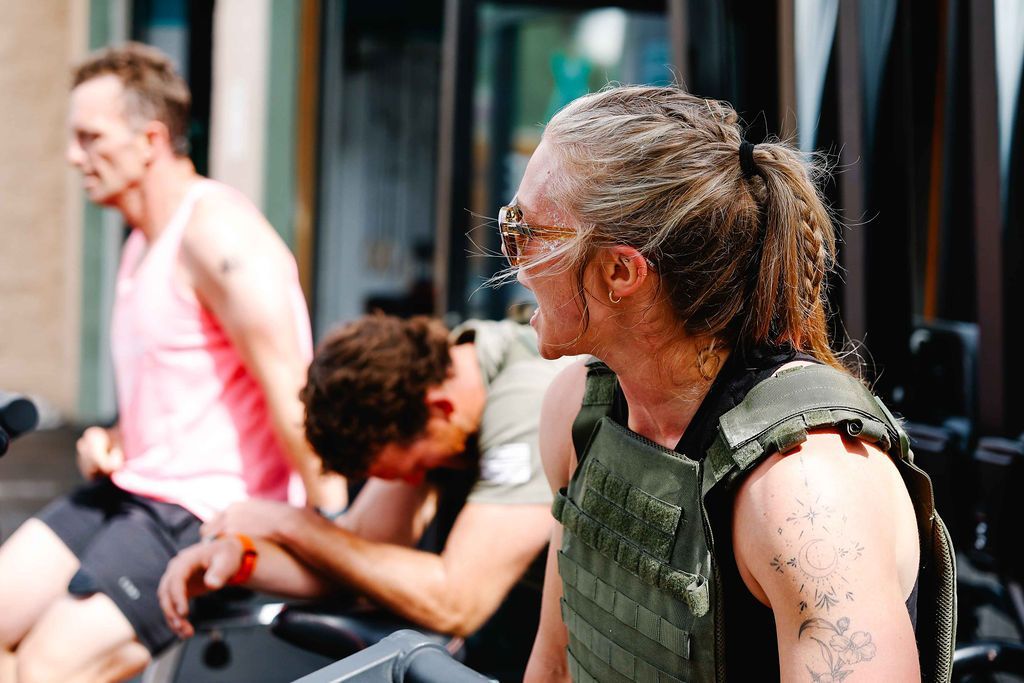 People resting after a workout, one in a green weighted vest, in a gym setting in Buena Vista, CO