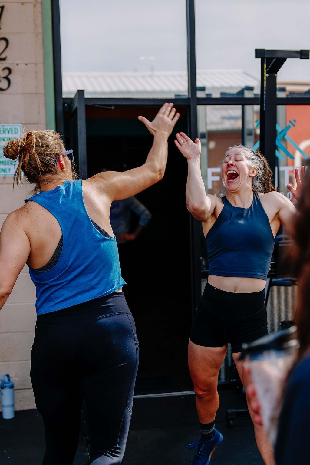 Two people in blue workout clothes high-five at Fortitude Fitness in Buena Vista, CO