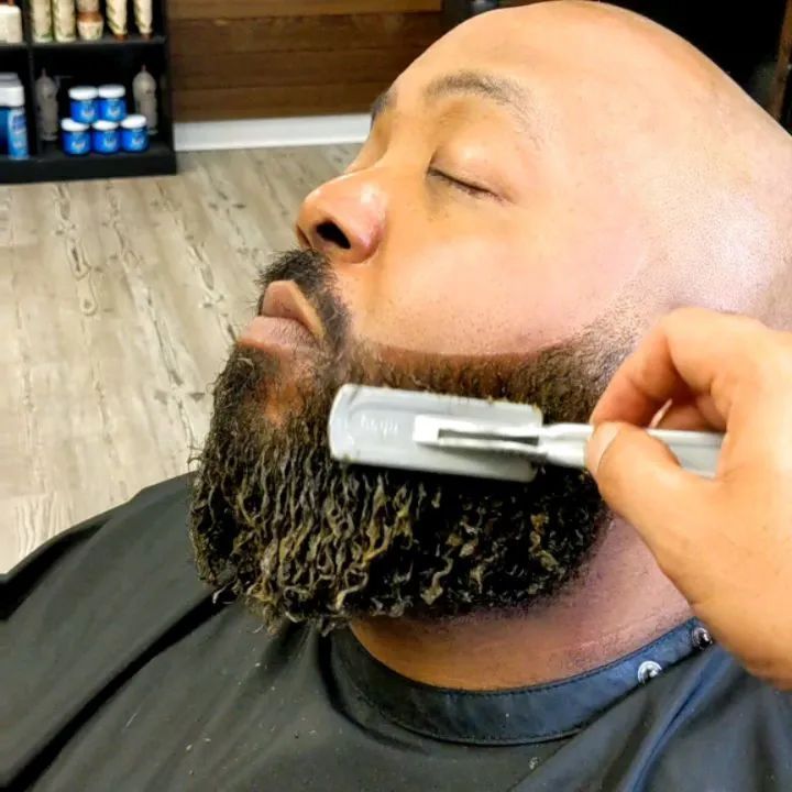 A man is getting his beard shaved with a razor