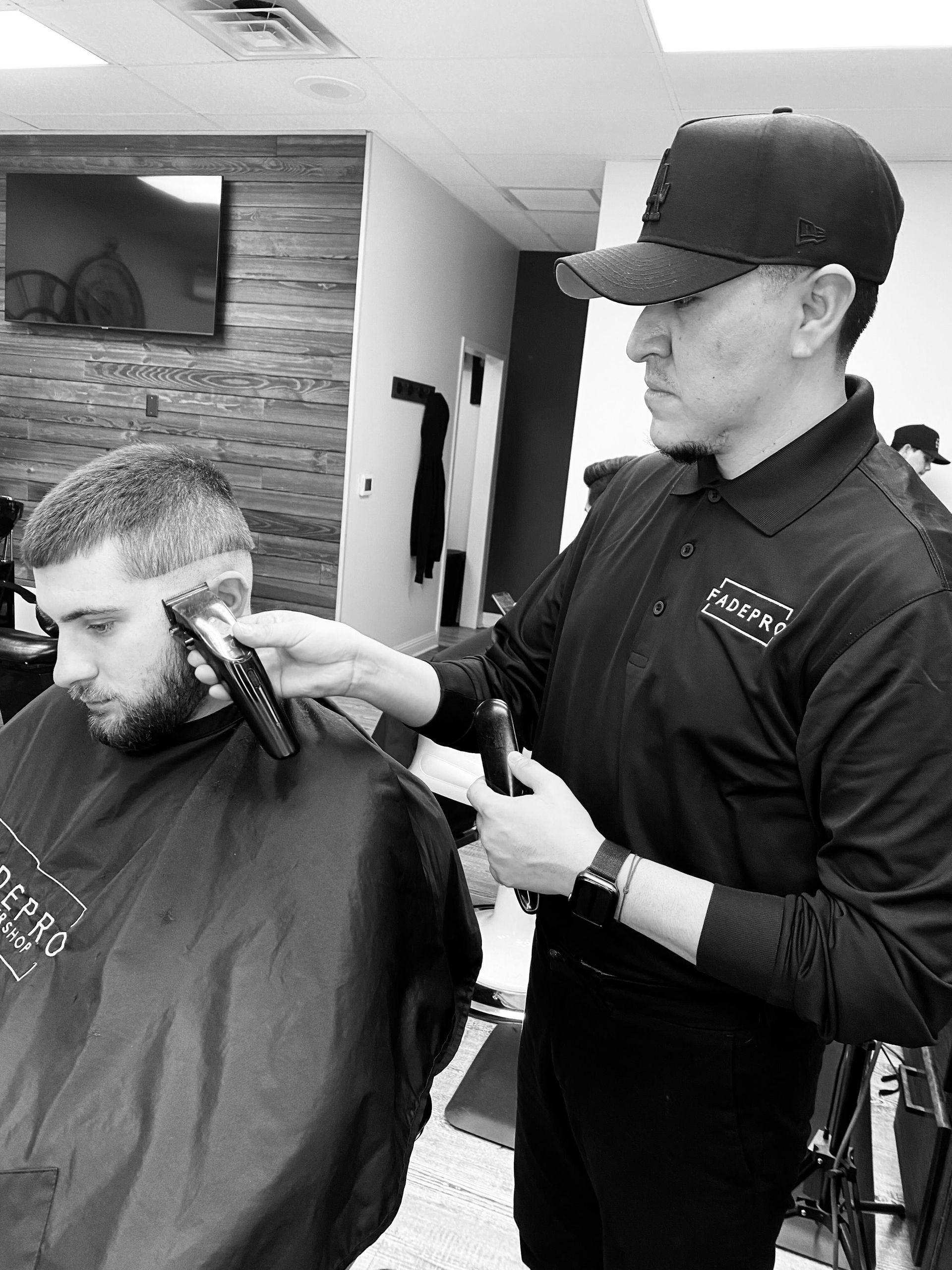 A man is getting his hair cut by a barber in a black and white photo.