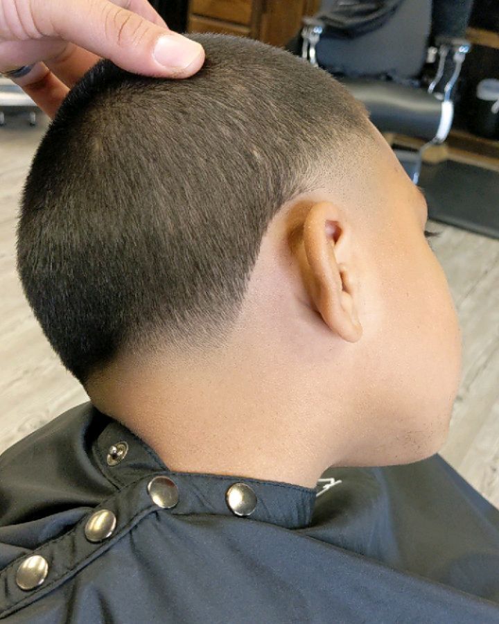 A young boy is getting his hair cut at a barber shop