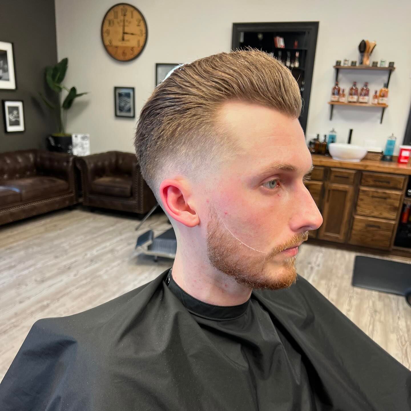 A man with a beard is getting his hair cut at a barber shop