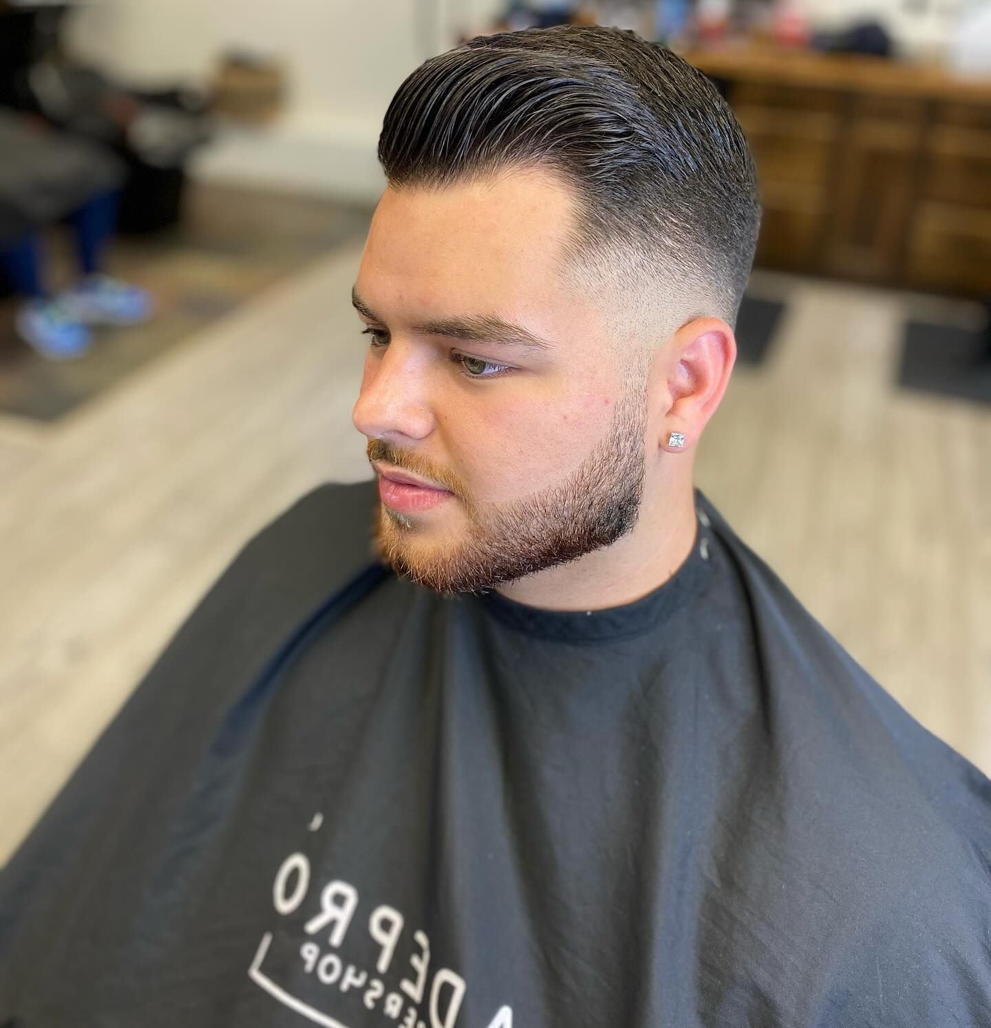 A man with a beard is getting his hair cut by a barber