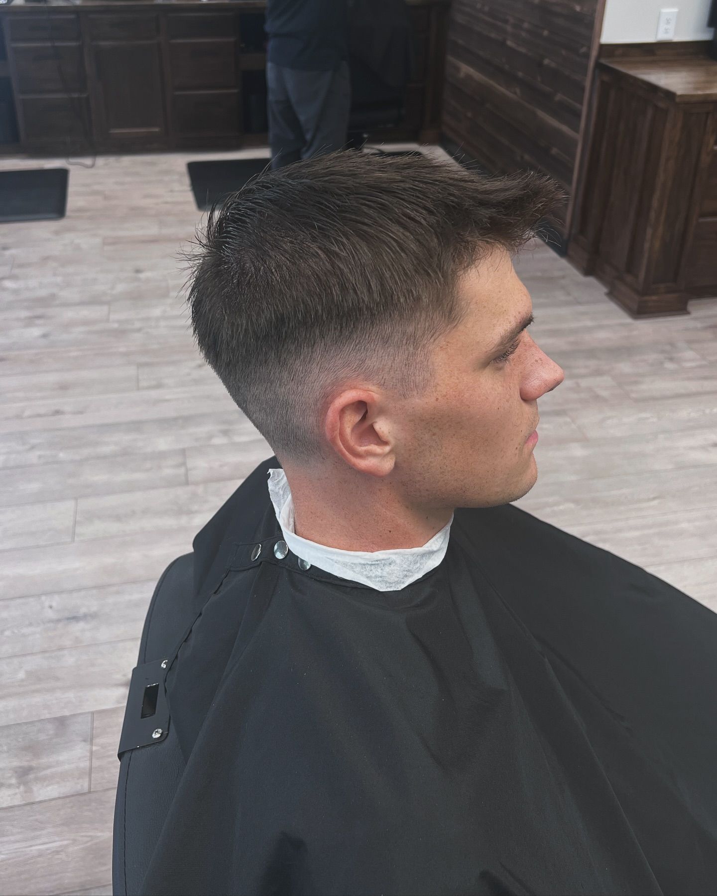 A man is getting his hair cut at a barber shop.