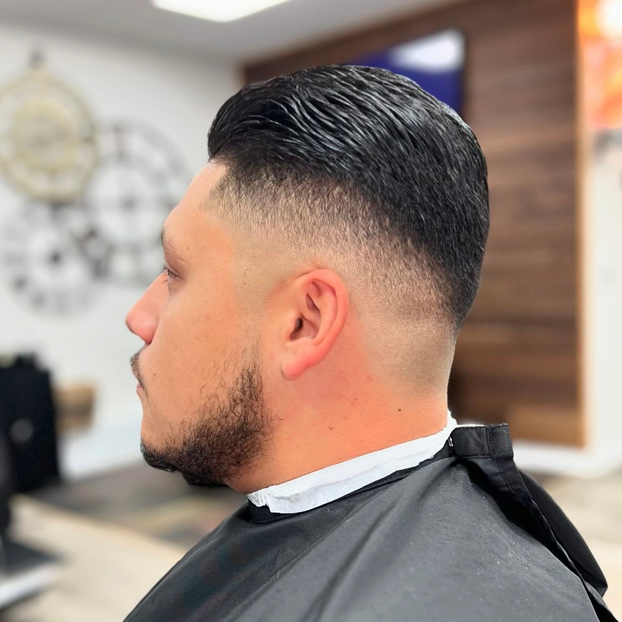 A man with a beard is getting his hair cut at a barber shop.