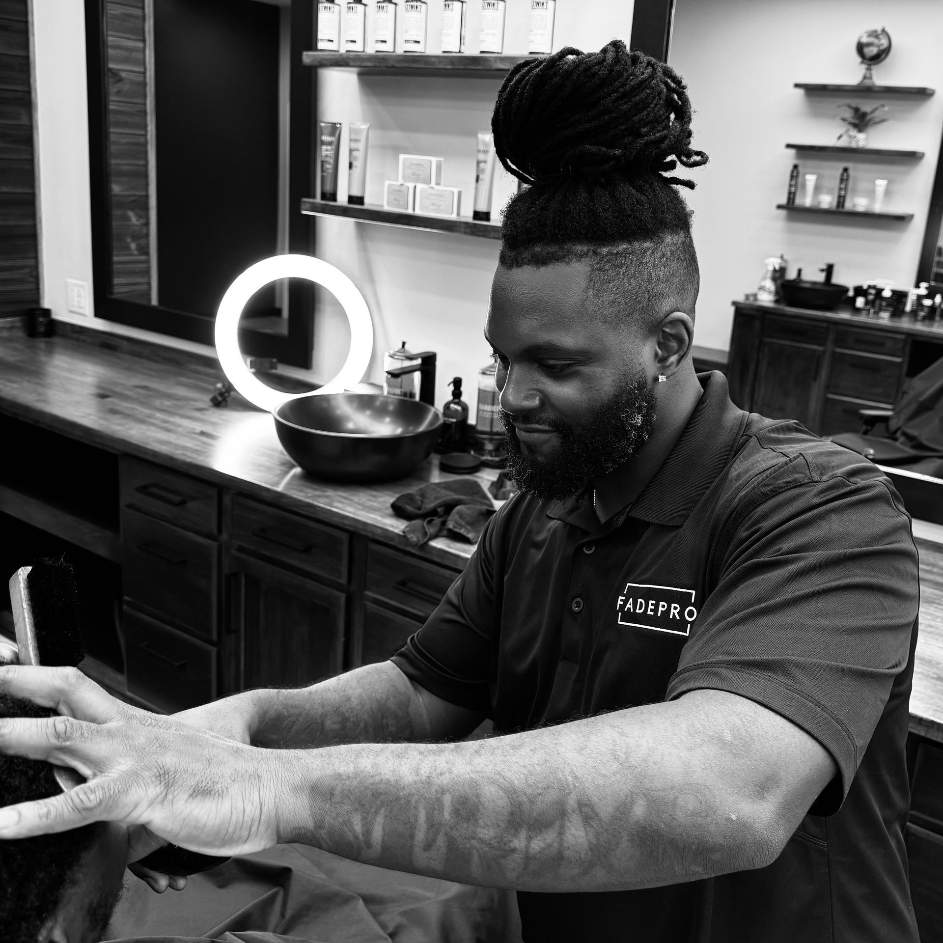A man is getting his hair cut by a barber in a black and white photo.
