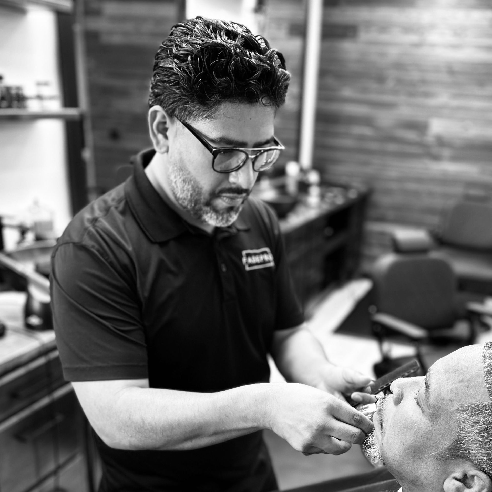 A black and white photo of a man getting his beard shaved by a barber