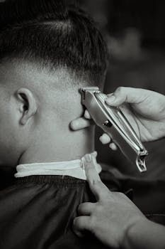 A man is getting his hair cut by a barber wearing a mask.