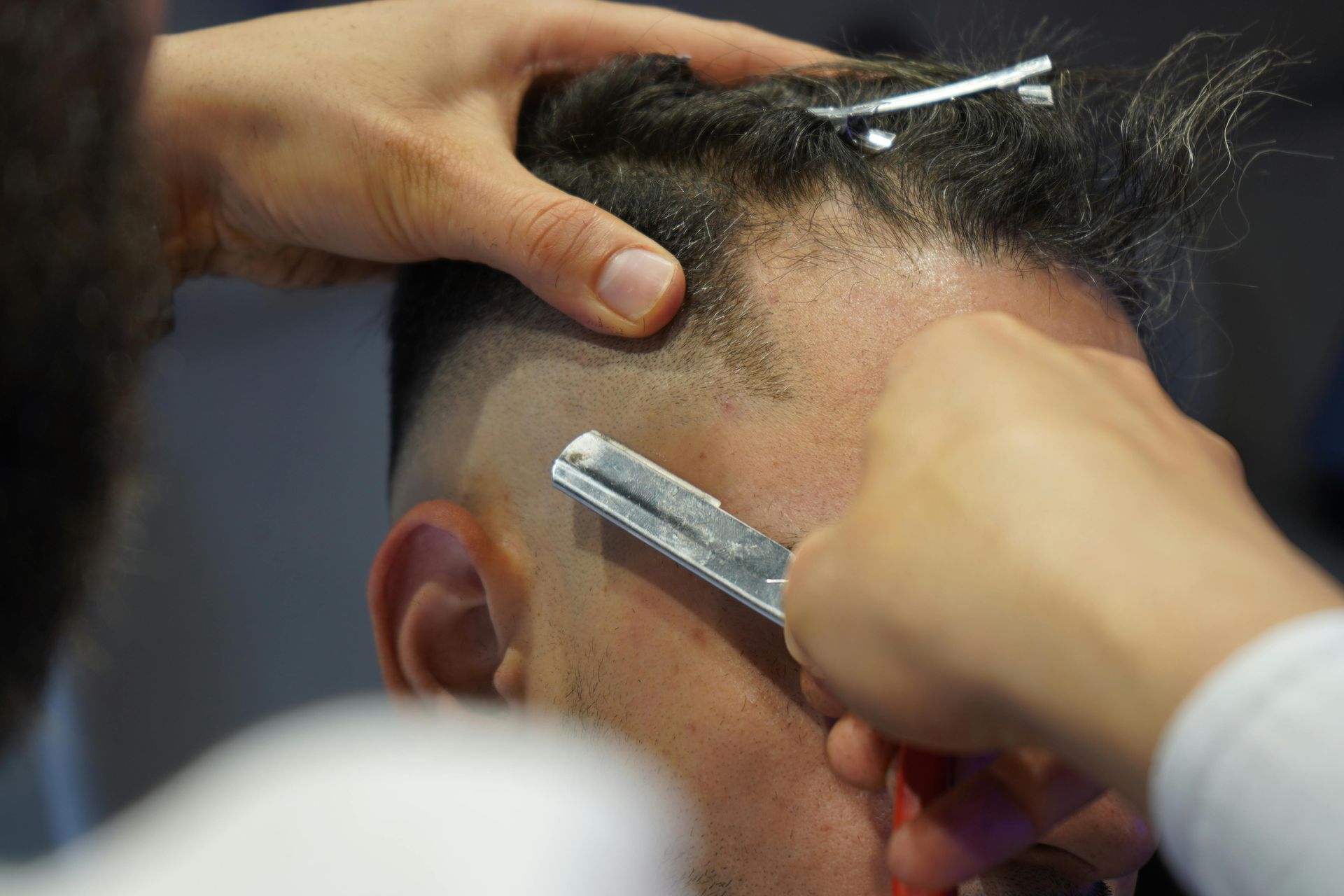 A man is getting his hair cut by a barber wearing a mask.