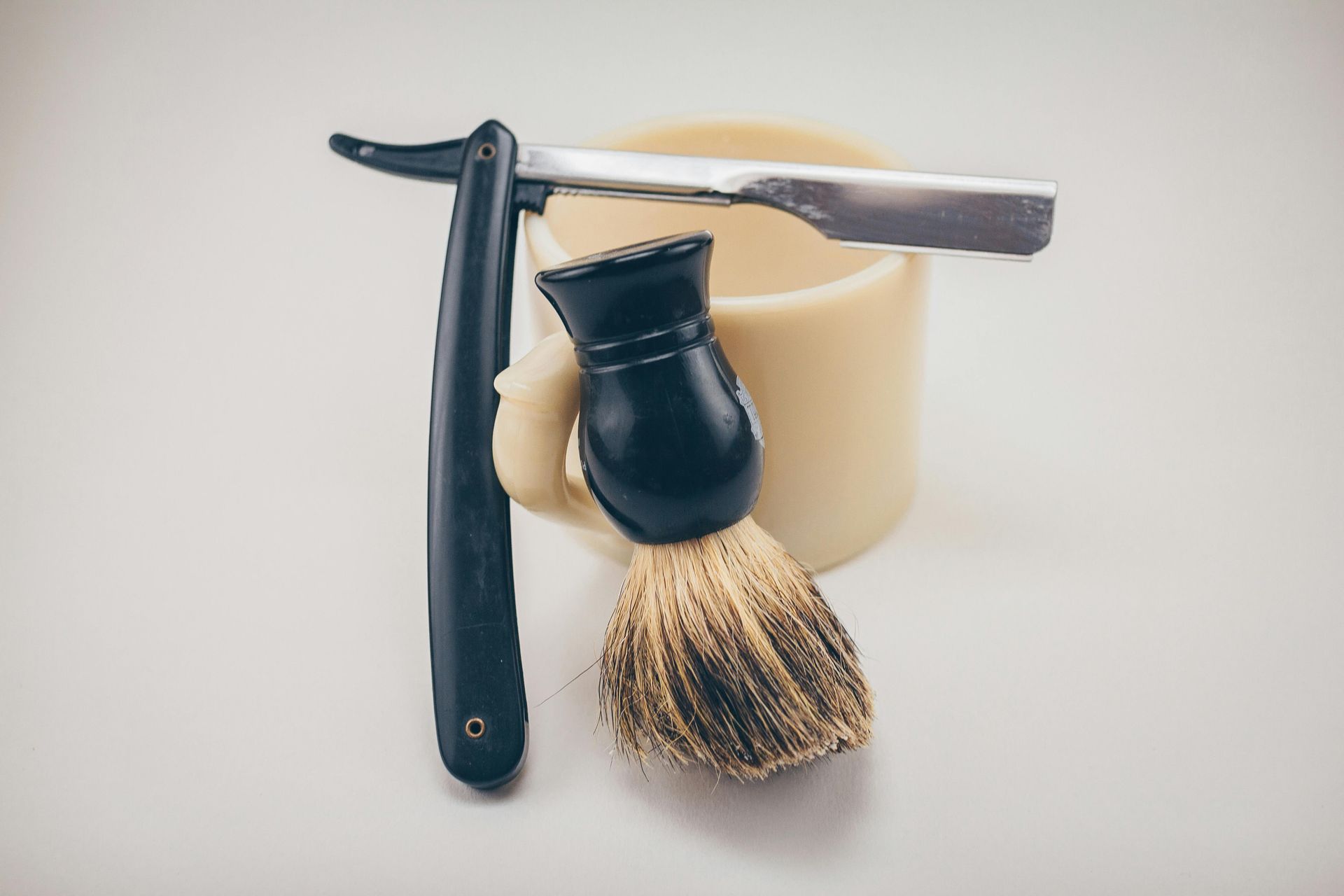 A razor and a shaving brush are sitting on top of a shaving mug.