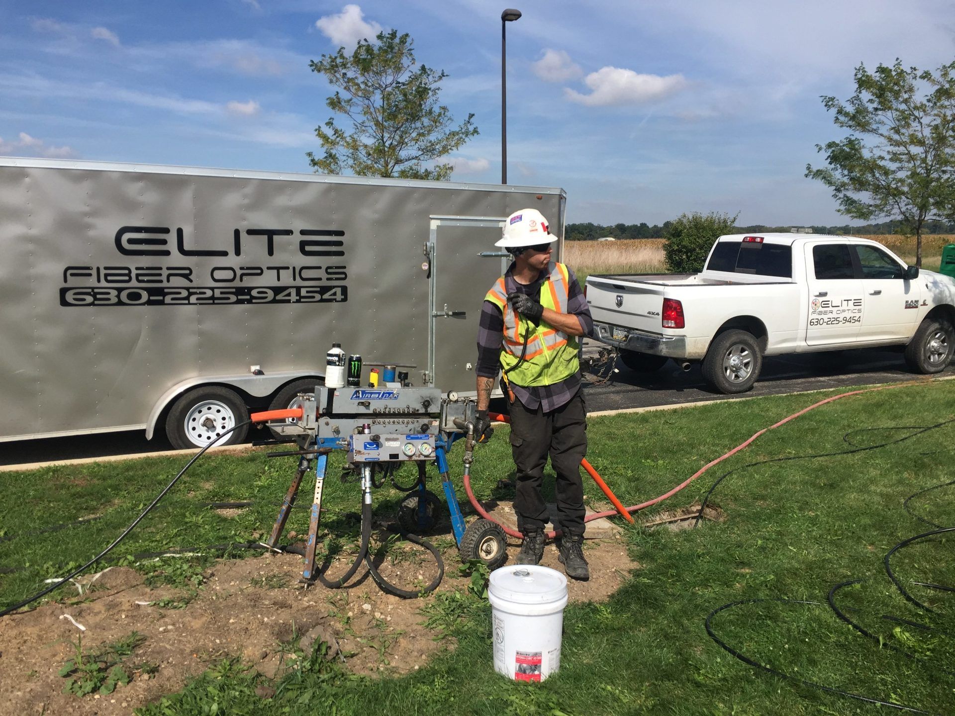 A man is standing in front of a trailer that says elite fiber optics.