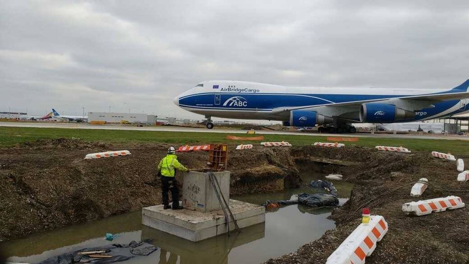 A man is standing in front of a large airplane on a runway.