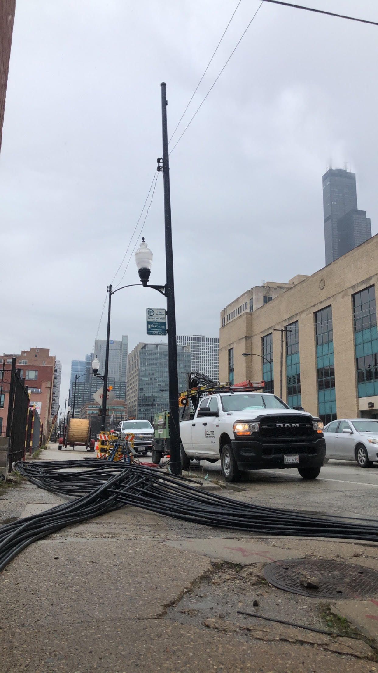 A white truck is driving down a city street next to a power line.