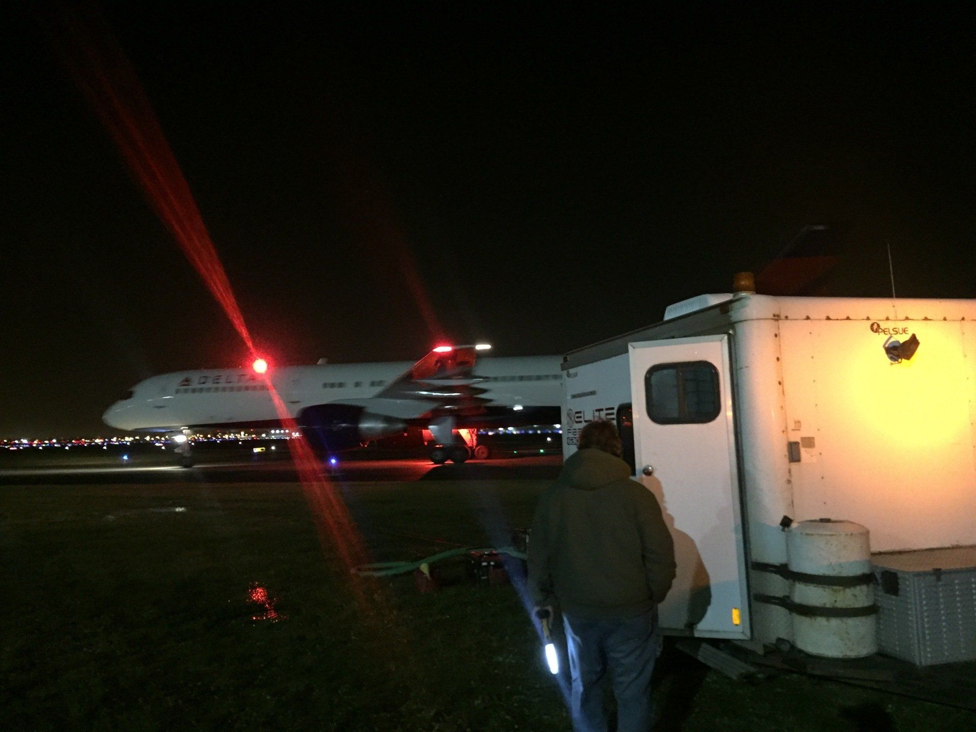 A man standing next to a trailer with a plane in the background