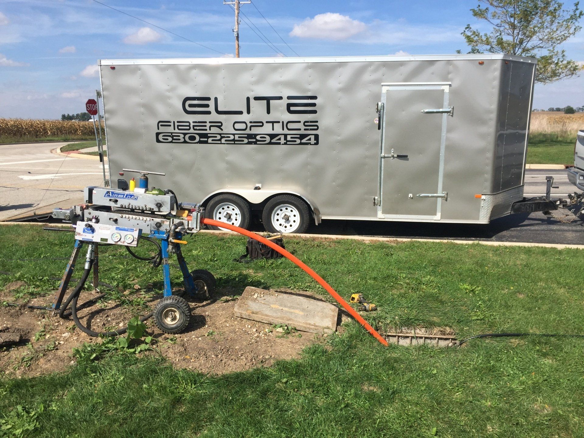 A trailer that says elite fiber optics is parked in the grass.