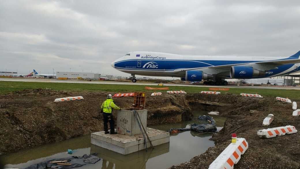 A large blue and white airplane is taking off from an airport runway.