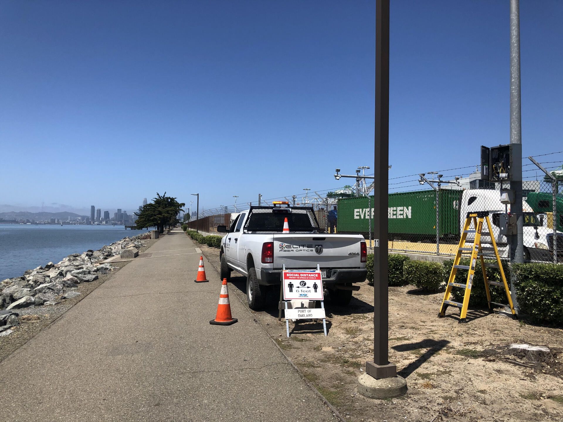 A white truck is parked on the side of a road next to a body of water.