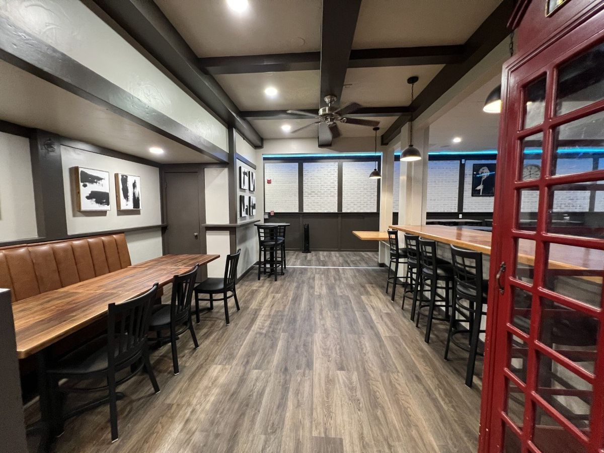 A restaurant with tables and chairs and a red phone booth.