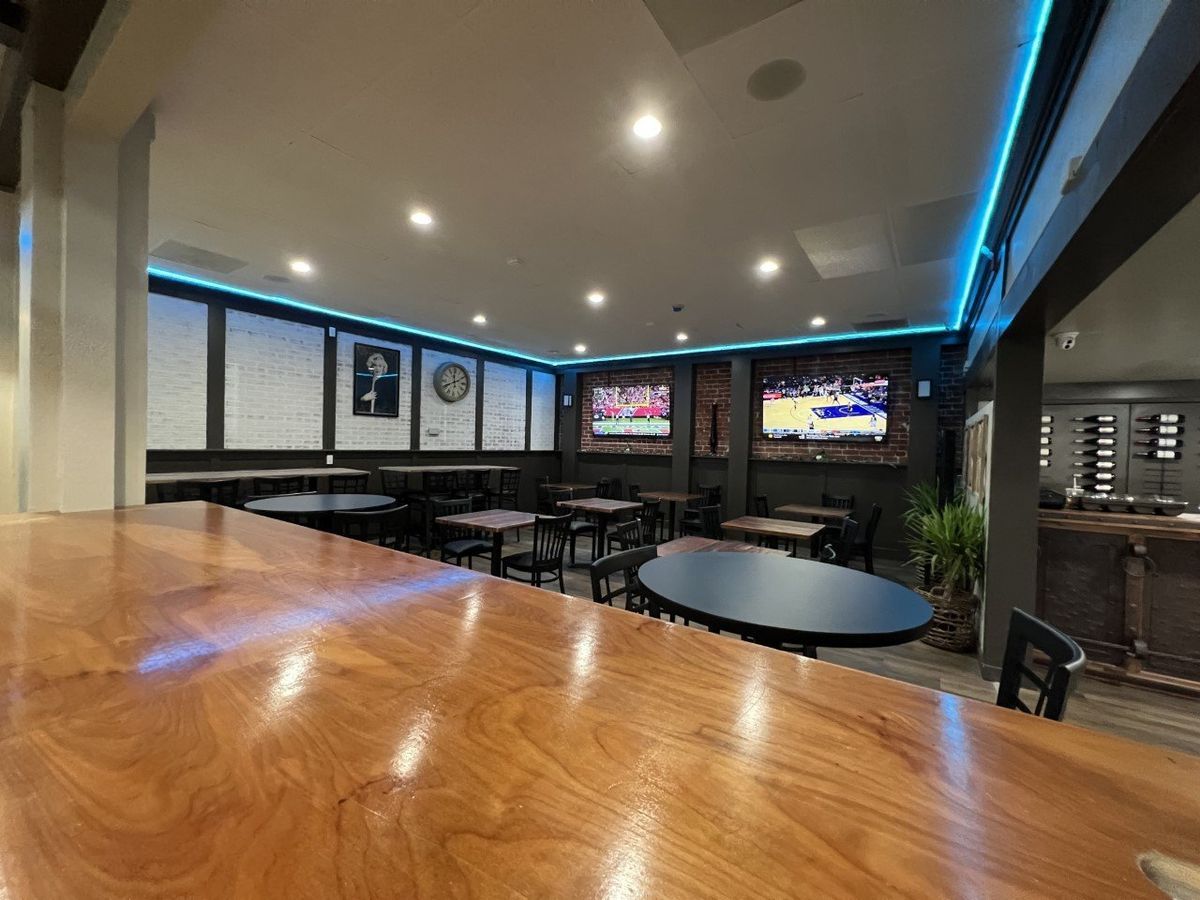 A restaurant with tables and chairs and two televisions on the wall.