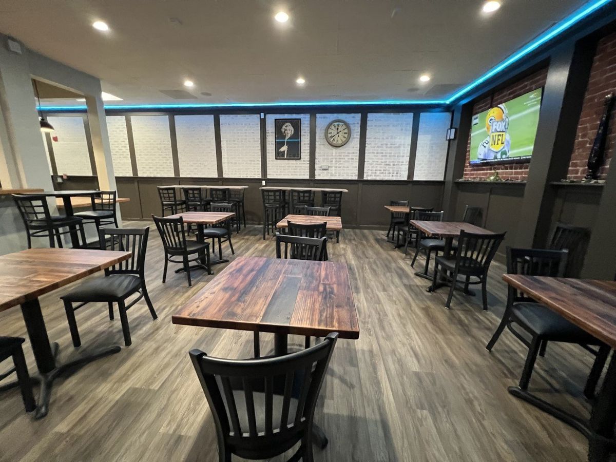 A restaurant with tables and chairs and a television on the wall.