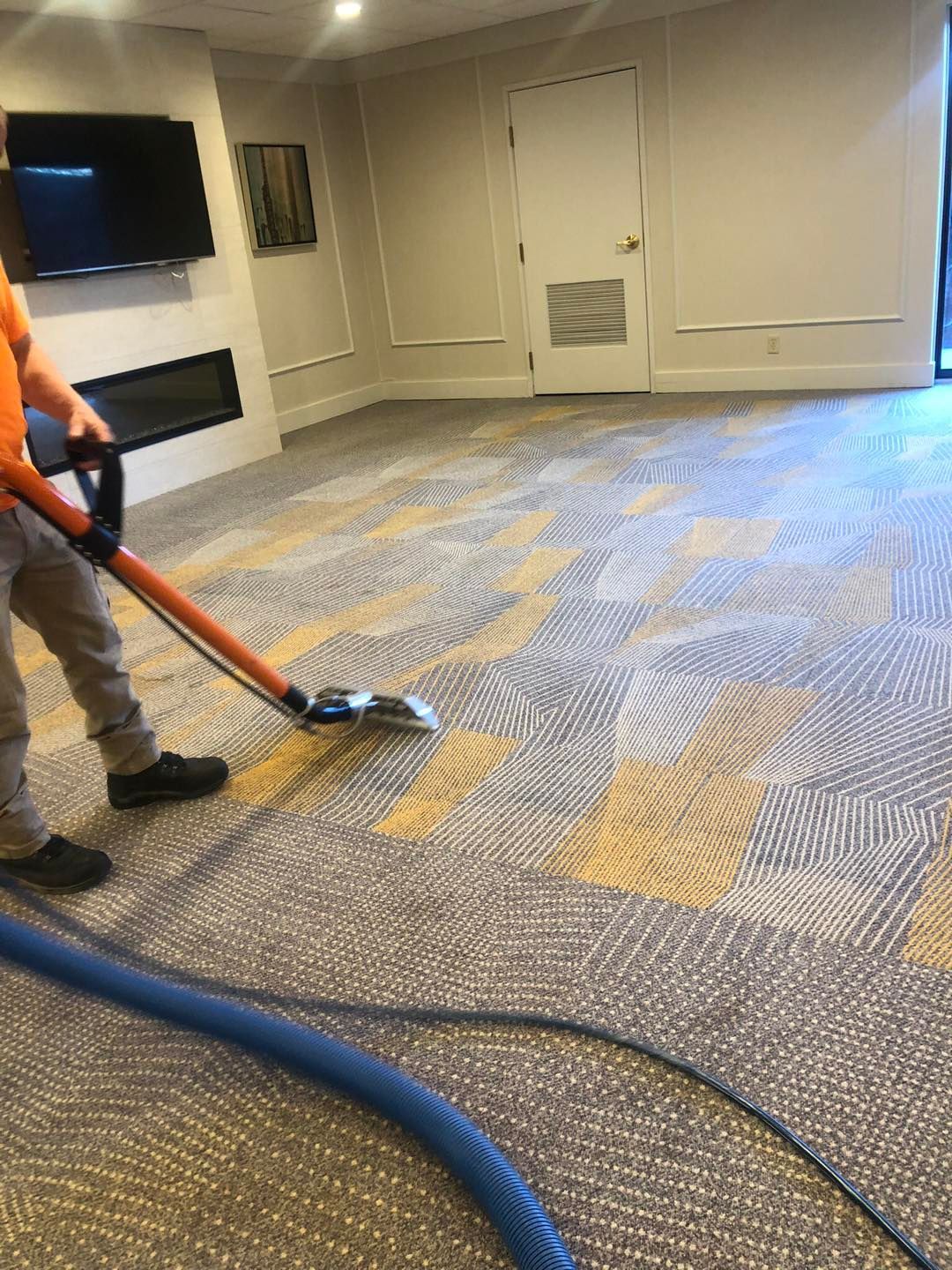 A man is cleaning a carpet with a vacuum cleaner in a room in Cleveland, Ohio.