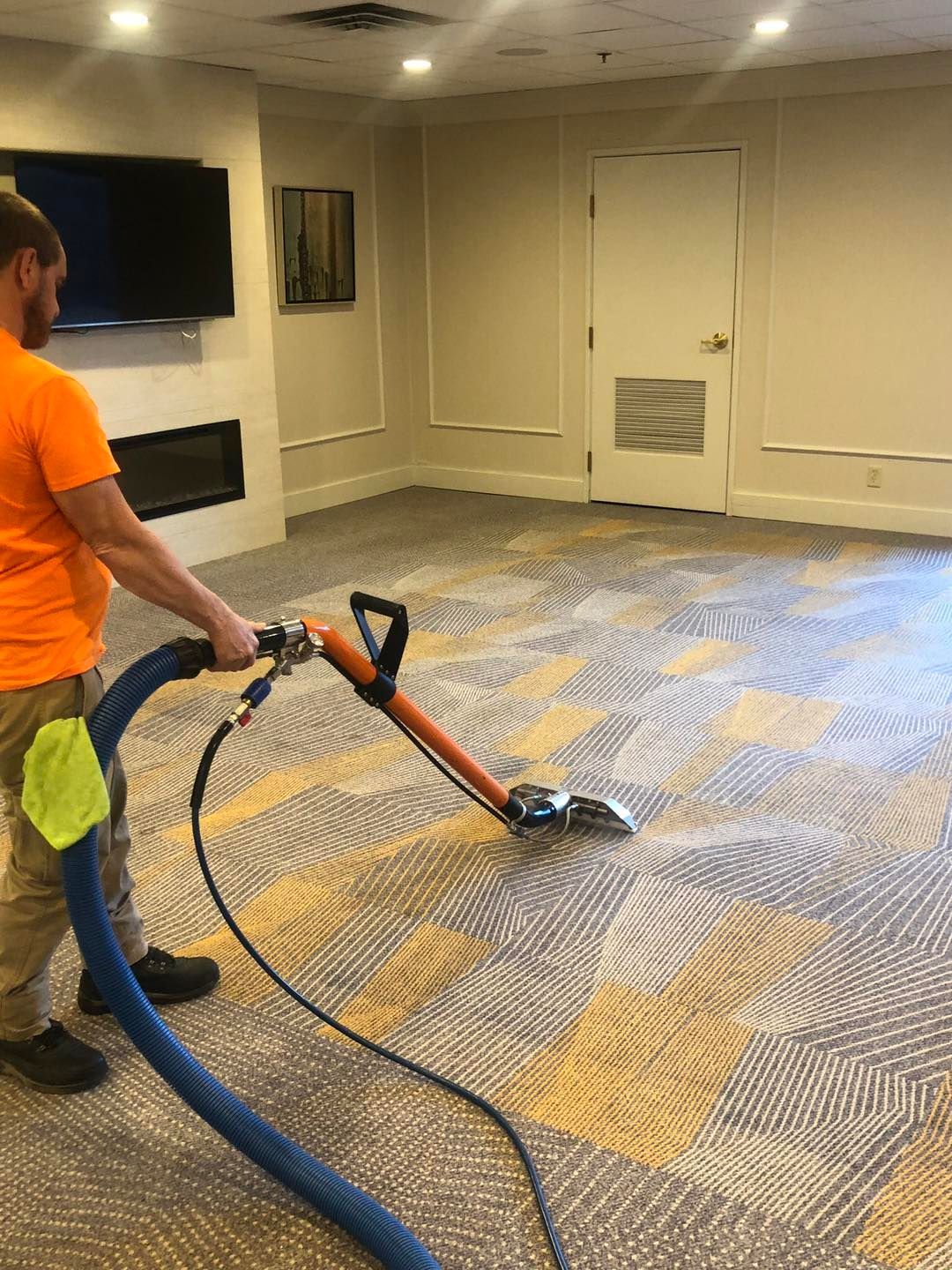 Man in orange shirt performing carpet cleaning near me in Cleveland, OH