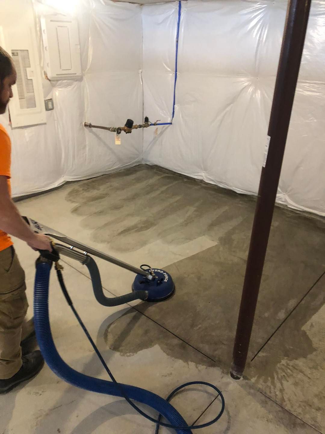 Man vacuuming the basement floor inside a Northeast Ohio residence.