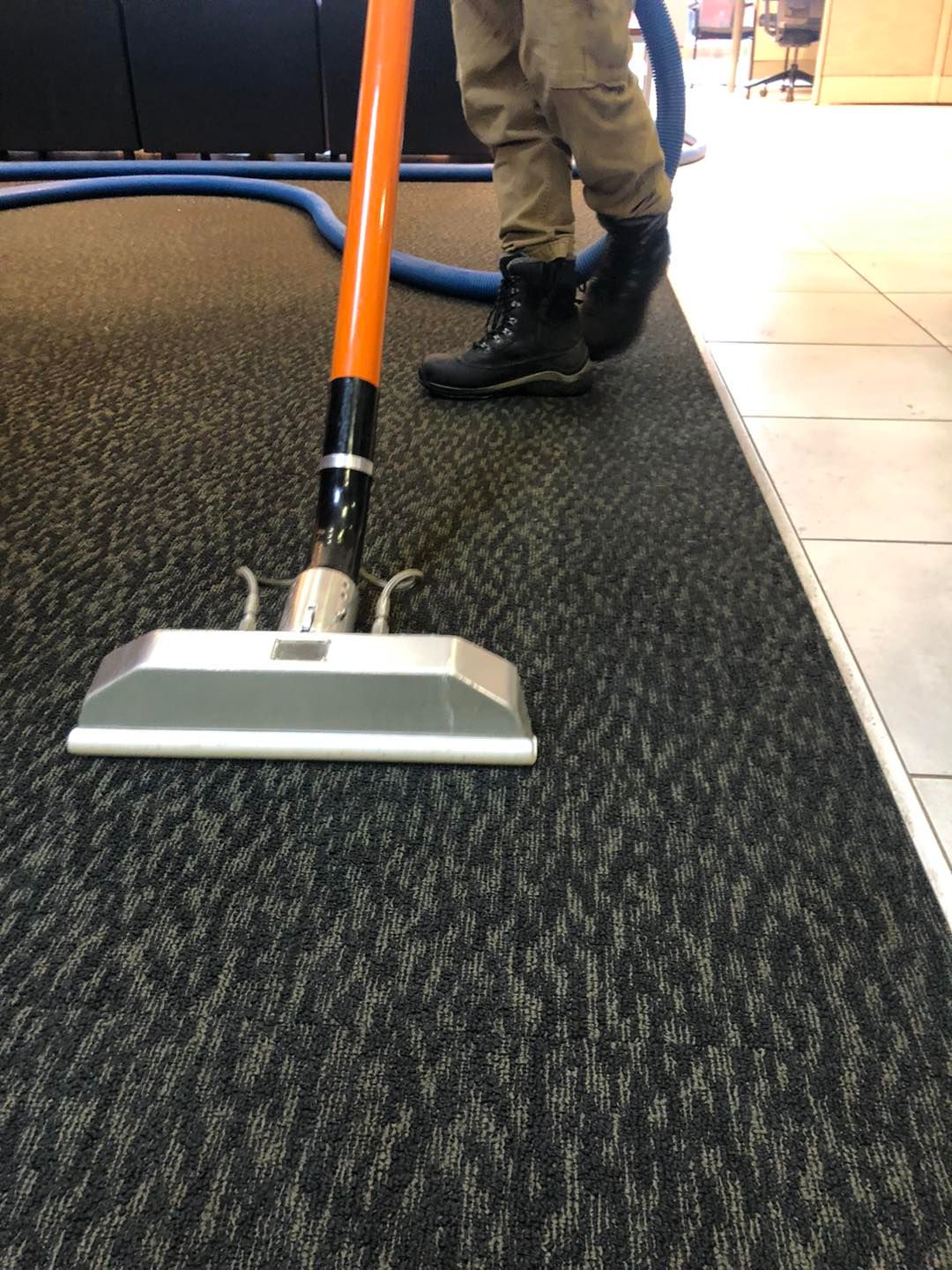Local Cleveland cleaning professional using a vacuum to clean carpeted flooring.