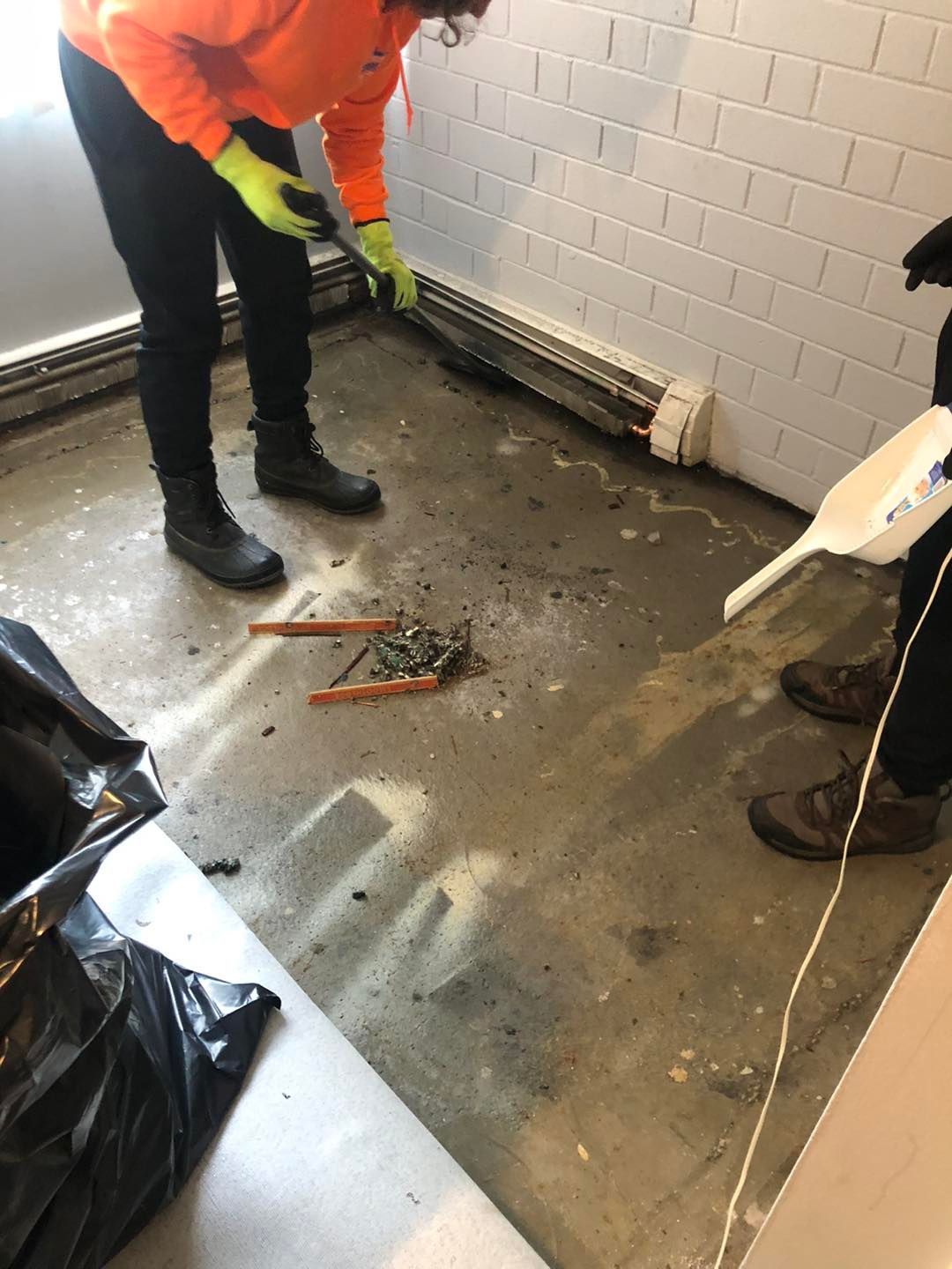 Person cleaning a floor with pliers during a task in a Cleveland‑area home.