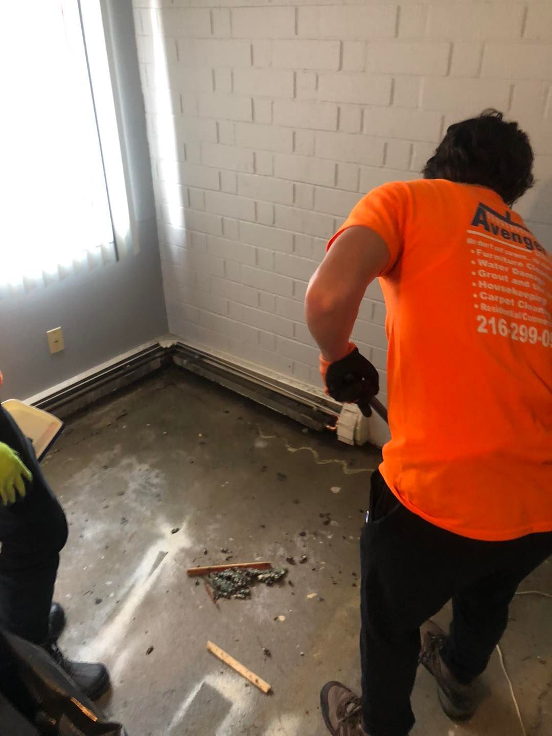 Cleaning technician in an orange shirt working on the floor of a residential room in Cleveland.