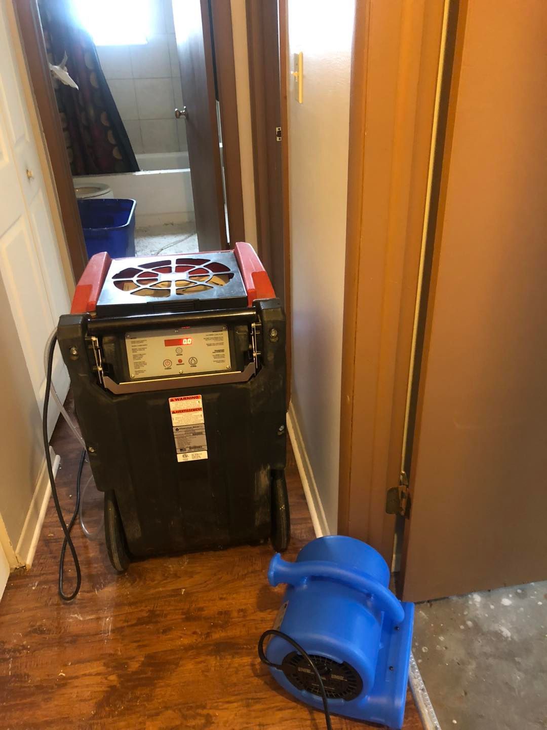 Restoration equipment on the hallway floor beside a blue fan in a Cleveland‑area property.