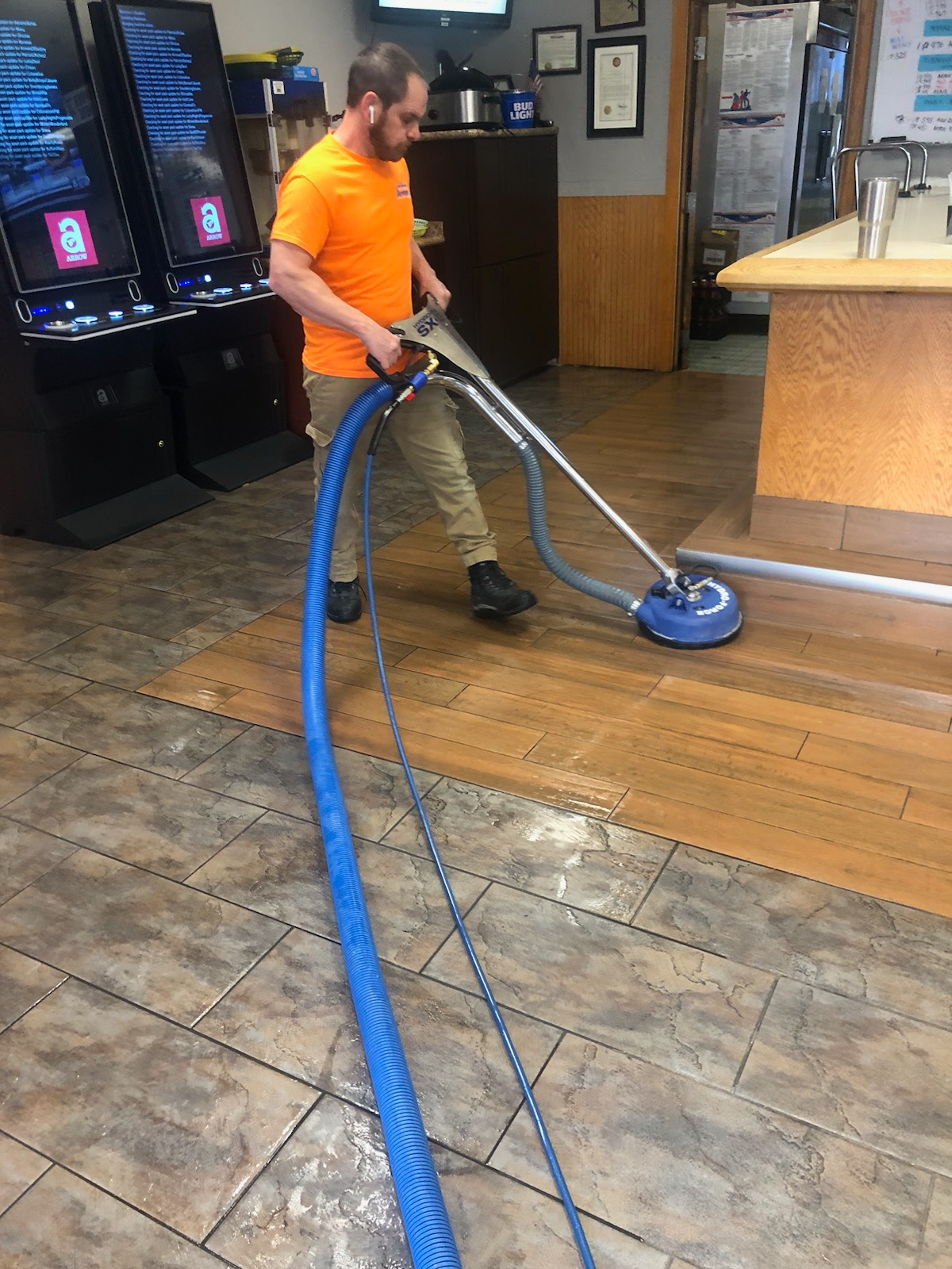 Professional floor cleaning technician vacuuming a tiled floor in a Cleveland home.