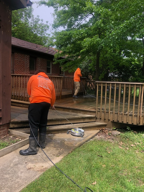 Two men performing residential deck cleaning near me in Cleveland, OH in front of a brick house