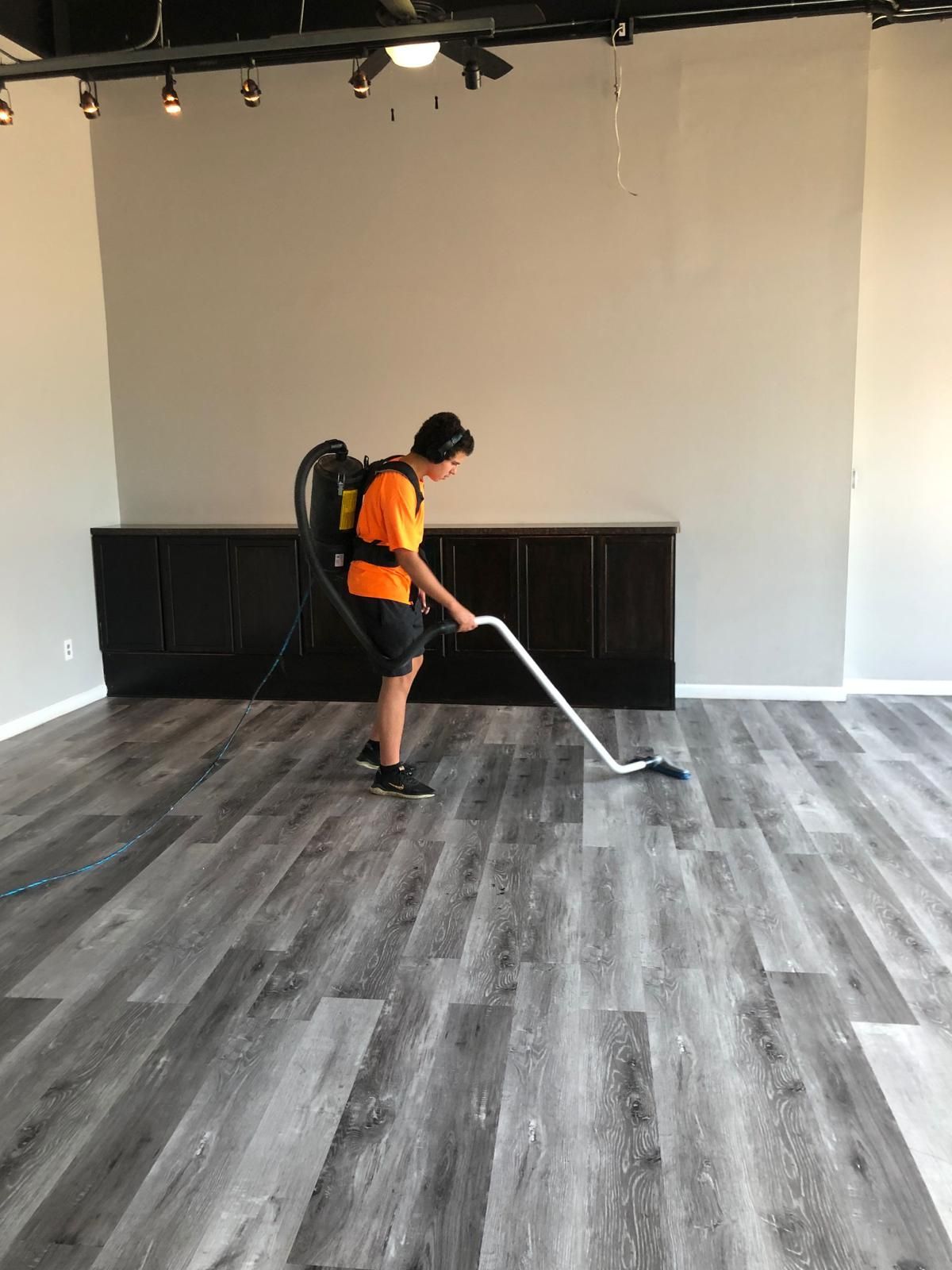 Professional carpet cleaner in an orange shirt vacuuming carpet for a Wickliffe homeowner