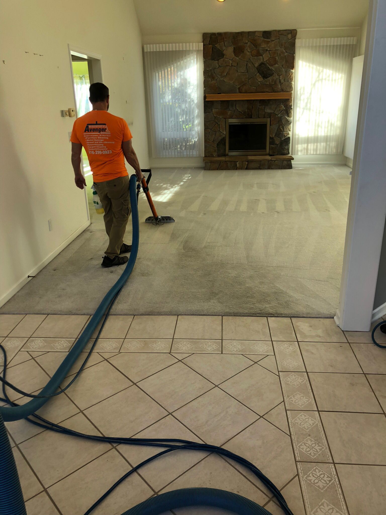 Local Cleveland carpet cleaner using a vacuum to clean a living room carpet during a residential service.
