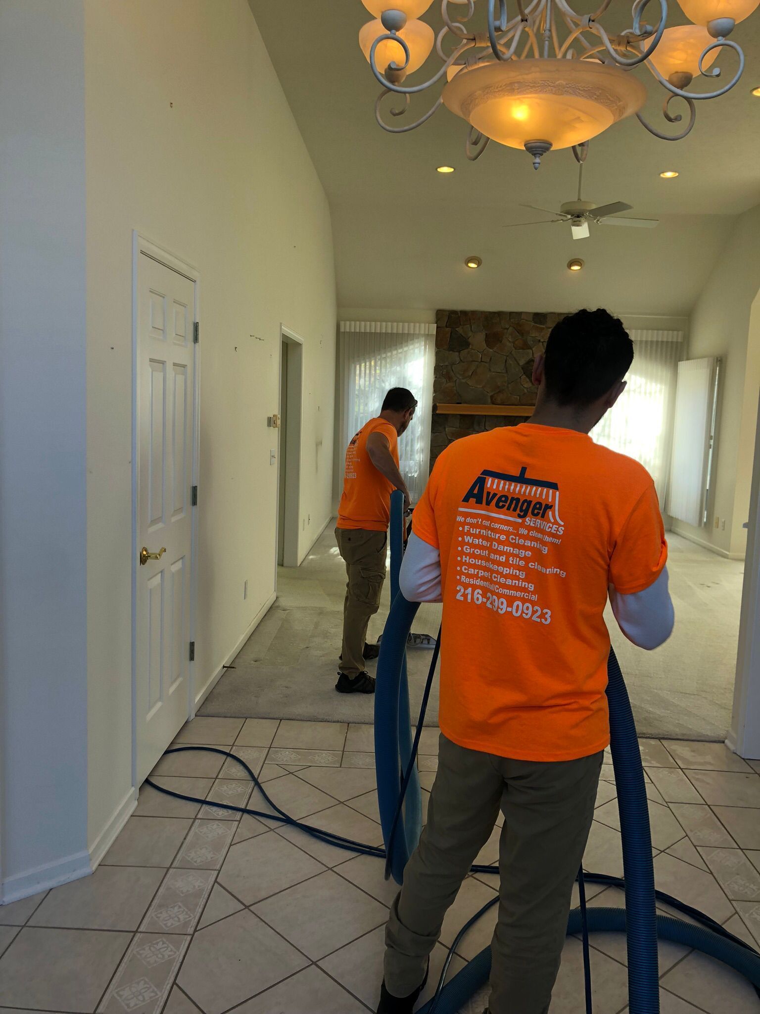 Local Cleveland floor cleaning technicians in orange shirts cleaning tile during a residential service.