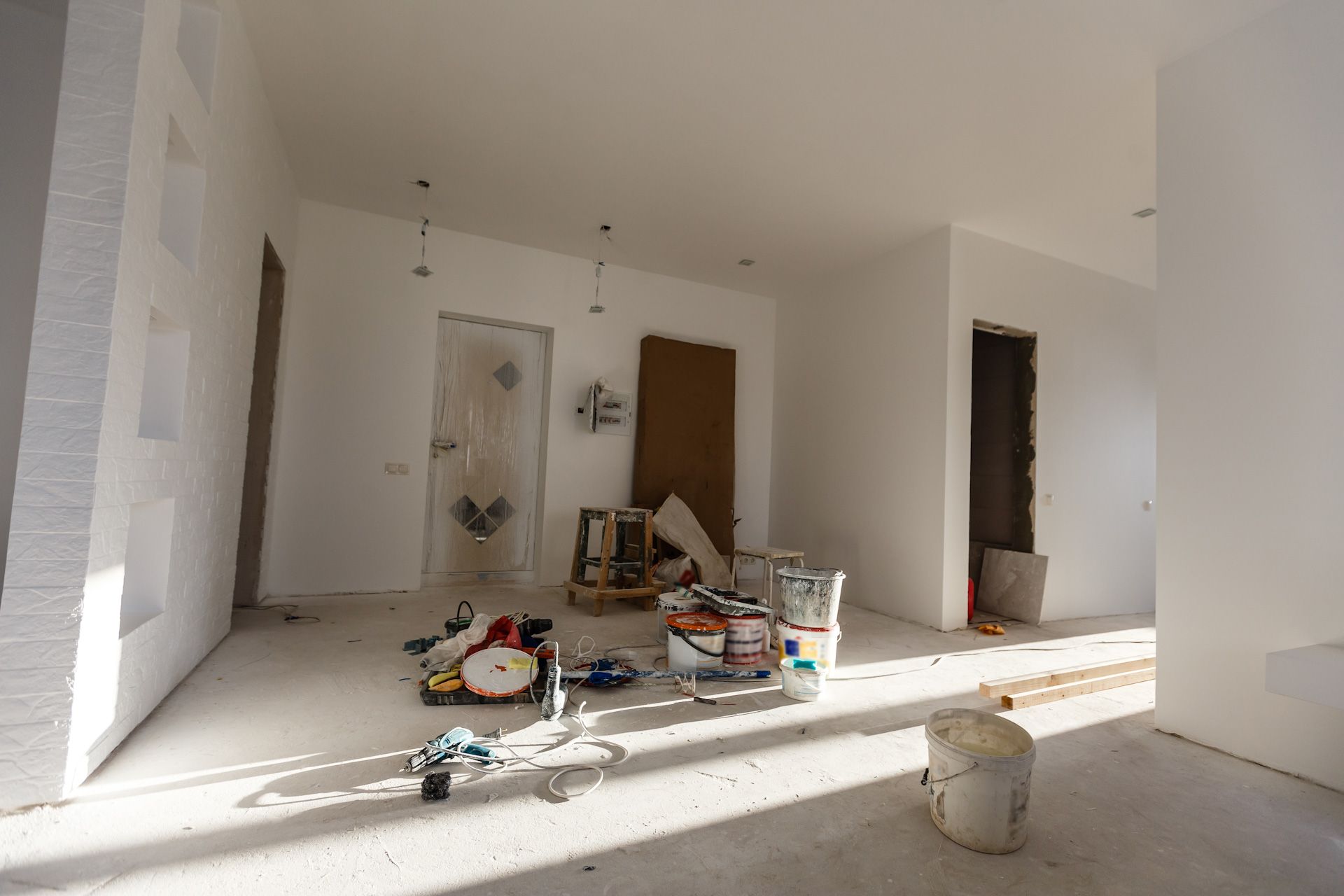 An empty room with buckets of paint and tools on the floor