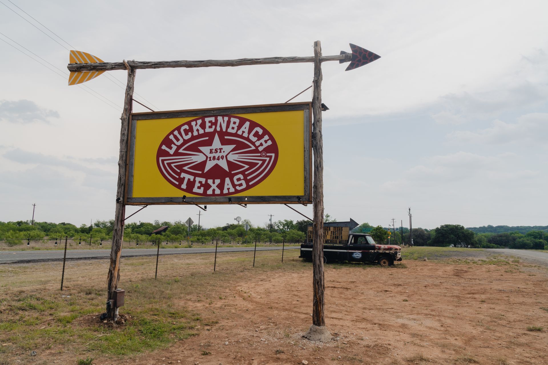 Buckden Ranch Texas sign on a rustic gate in a field with a truck nearby
