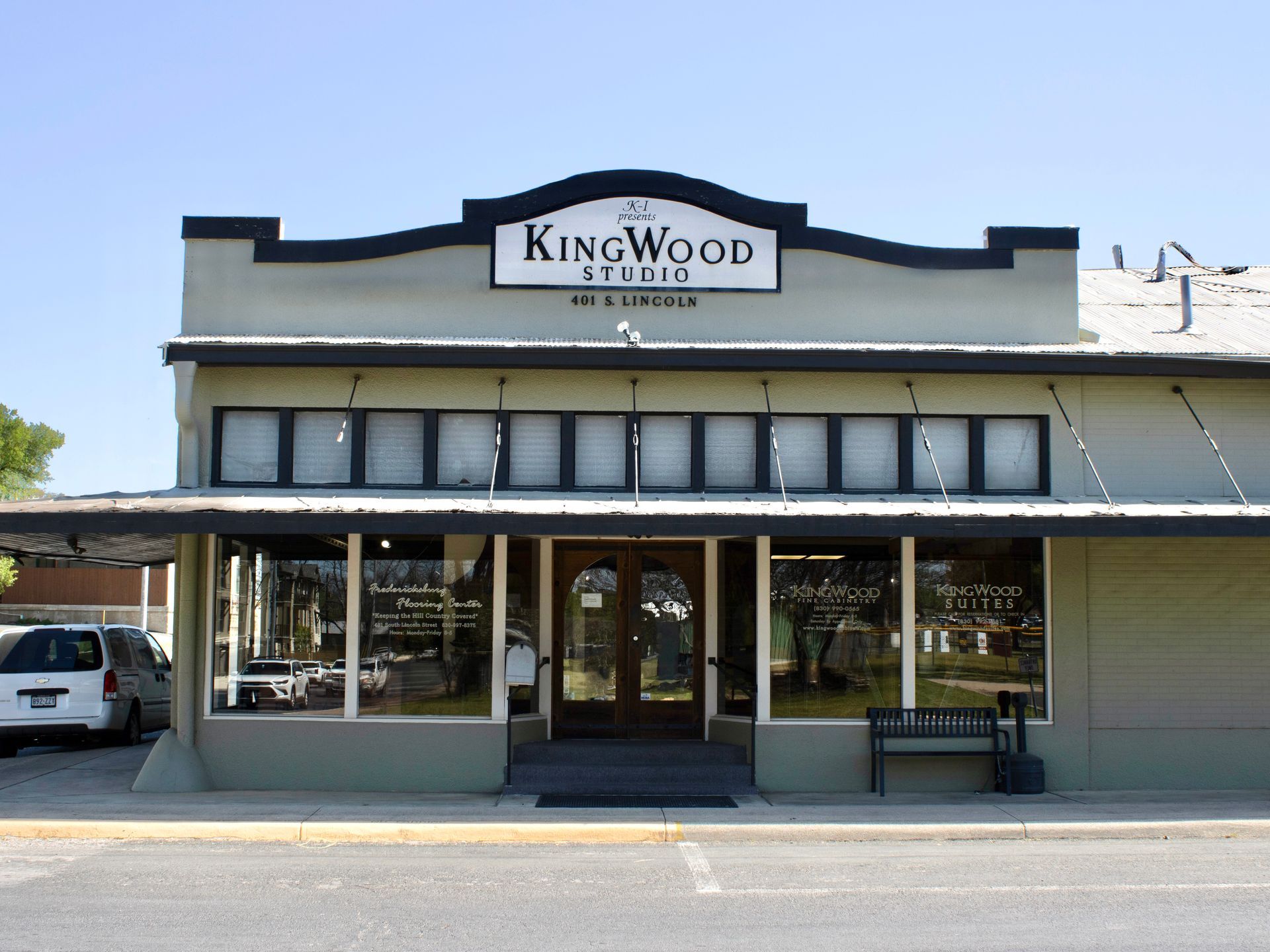 Kingwood sign above a storefront with white awning and glass windows on a sunny street