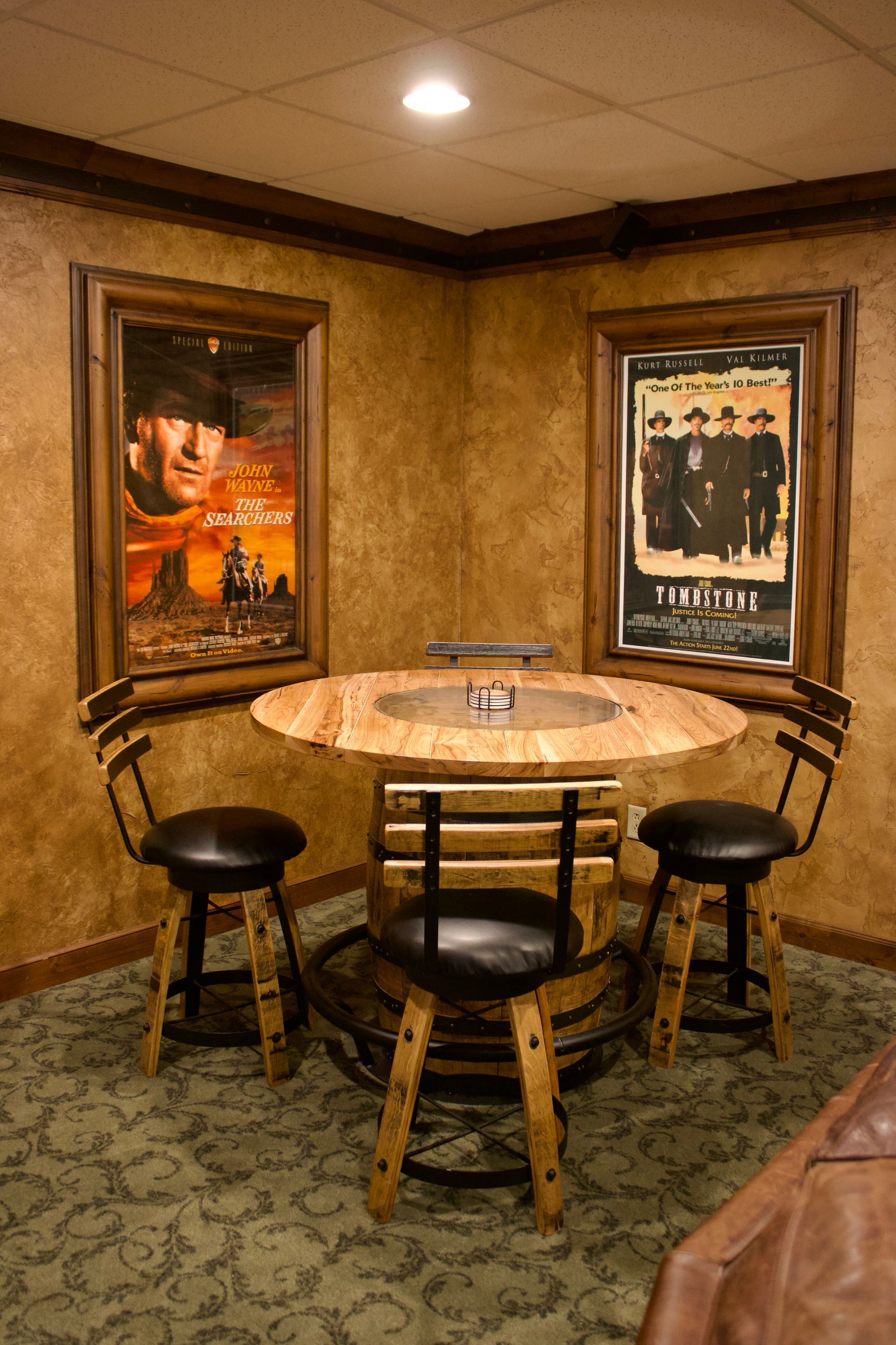 Small café corner with a round wooden table, stools, wall art, and warm tan walls.