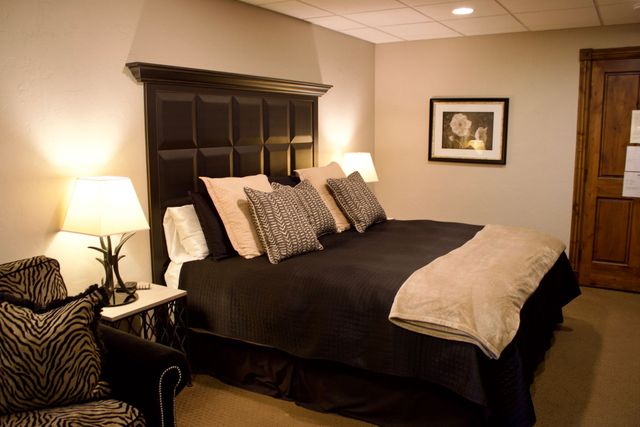 Cozy bedroom with a bed, lamp, patterned chair, and framed wall art in warm tones