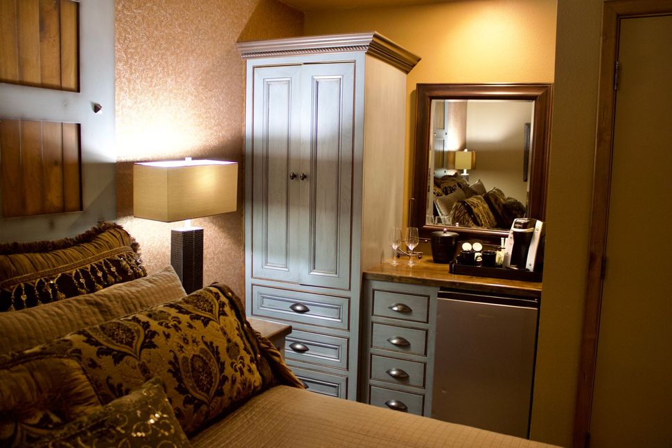 Cozy bedroom with patterned pillows, lamp, white wardrobe, and vanity mirror
